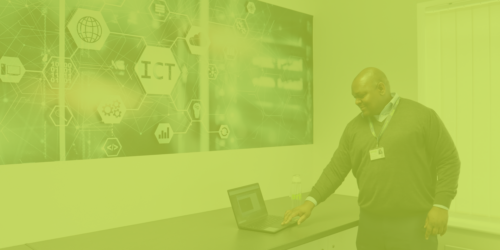 Digital Trainer, Admire, standing at the IT workbench. There is a green overlay on the image.